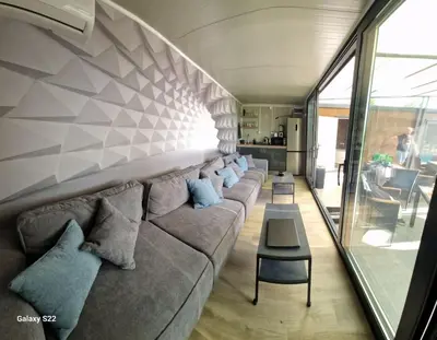 a living room with a long gray couch with pillows at Niki Hill in Železnička Stanica Karlovački Vinogradi