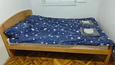 a bed with a blue sheet with stars on it at hometown in Pančevo