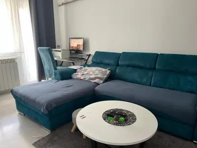 a living room with a blue couch and a table at Apartman 100m2 in Belgrade