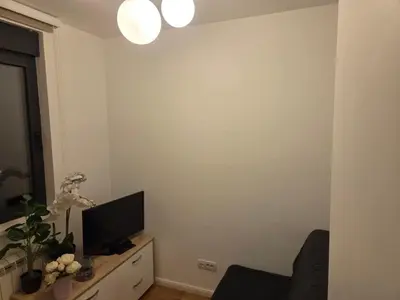 a living room with a tv on a white wall at Apartman-Stan in Belgrade