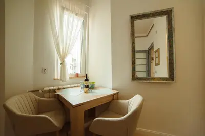 a dining room table with chairs and a mirror at Mizi Apartment in Belgrade