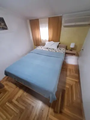 a large bed in a small room with wooden floors at Rooms3 in Beograd