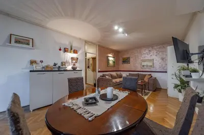 a living room with a wooden table and a kitchen at Ada Home Belgrade Apartment