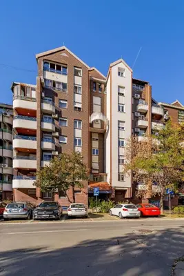 a large apartment building with cars parked in a parking lot at Ada Home Belgrade Apartment