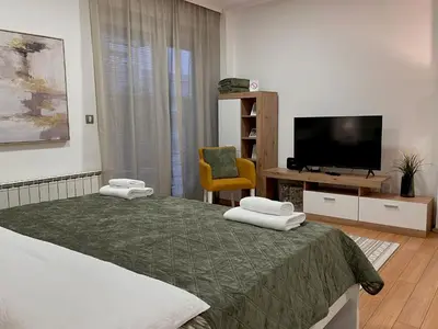 a bedroom with a bed with a television and a chair at Liberte Apartments 2 Voždovac in Belgrade