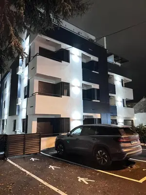 a black car parked in a parking lot in front of a building at Apartman Beograd in Belgrade