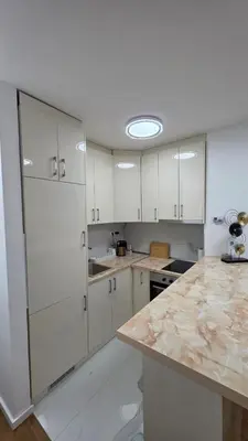 a kitchen with white cabinets and a marble counter top at Apartman Beograd in Belgrade