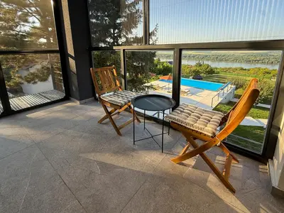 a balcony with two chairs and a table and a pool at Villa Vista Slankamen in Stari Slankamen
