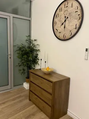 a clock on a wall above a wooden dresser at WhiteCity Suite in Belgrade