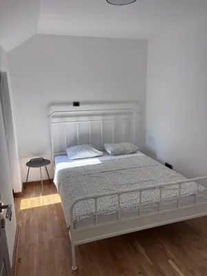 a white bed in a bedroom with a wooden floor at Pejton Apartment in Belgrade