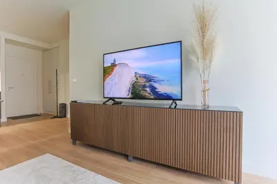 a flat screen tv on a wooden stand in a living room at The Sensation Belgrade Waterfront in Belgrade