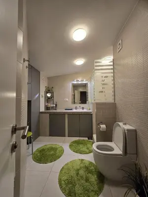 a bathroom with a toilet and green mats in it at Crown Apartment in Belgrade