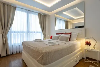 a white bedroom with a large bed and a window at Bw Lux Apartments River view in Belgrade