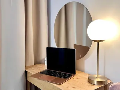 a laptop on a wooden table with a lamp and a mirror at NookLite Studio near Belgrade Arena in Belgrade