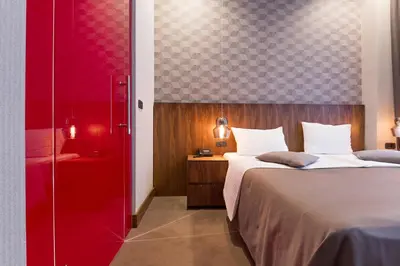 a bedroom with two beds and a red wall at Five Points Square - City Center in Belgrade