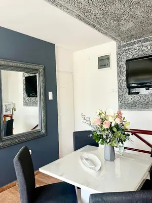 a white table with a vase of flowers and a mirror at Guesthouse Vladimir & Ana in Pančevo