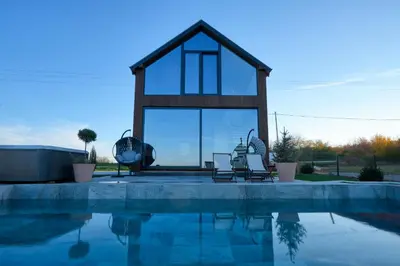 a swimming pool with two chairs and a house at Oasis Pool House