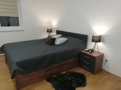a bedroom with a bed and a nightstand with two lamps at Soft Loft cozy studio with a garage parking place in Belgrade