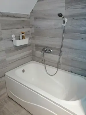 a white bath tub with a shower in a bathroom at Soft Loft cozy studio with a garage parking place in Belgrade