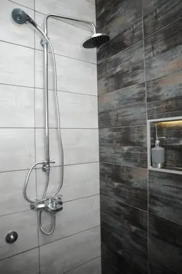 a shower in a bathroom with a wooden wall at Gala Luxury Suites in Belgrade