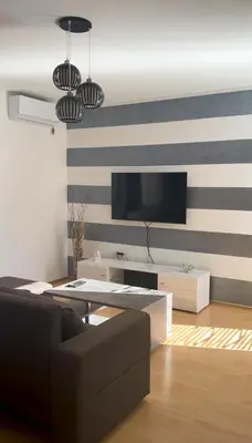 a living room with a tv on a striped wall at Apartman Lav in Bele Vode