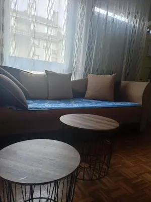 a couch with two tables in front of a window at New Year Loft in Belgrade