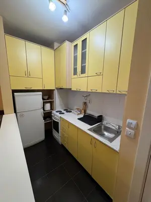 a small kitchen with yellow cabinets and a sink at Apartment 63 in Belgrade