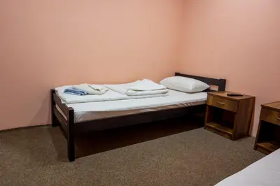 a bedroom with a bed with white sheets and a night stand at Etno kompleks Deliblatska Čarda in Deliblato