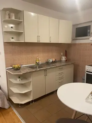 a kitchen with white cabinets and a sink and a table at Roza in Ruma