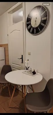 a white table with chairs and a clock on the wall at Roza in Ruma