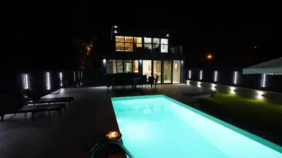 a swimming pool in front of a house at night at River House Sunrise in Ritopek