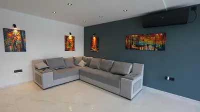 a living room with a couch and paintings on the wall at River House Sunrise in Ritopek