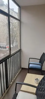 a balcony with a table and chairs and a large window at LP apartment in Belgrade