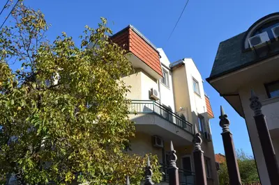 a building with a balcony next to a tree at Villa K Apartments in Belgrade