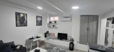 a white living room with a tv and a couch at Slavuj MINI in Belgrade