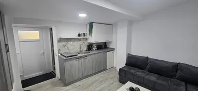 a living room with a black couch and a kitchen at Slavuj MINI in Belgrade