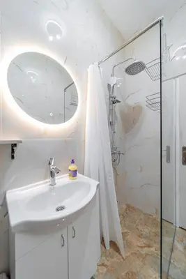 a white bathroom with a sink and a shower at Nele Belgrade Apartment in Belgrade
