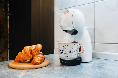 a coffee maker pouring coffee into a cup with croissants at Foosball Frontyard Retreat Old Town in Belgrade