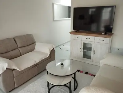 a living room with a couch and a tv and a table at VauDa White apartman in Belgrade