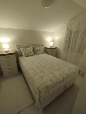 a bedroom with a bed and two dressers and two lamps at VauDa White apartman in Belgrade