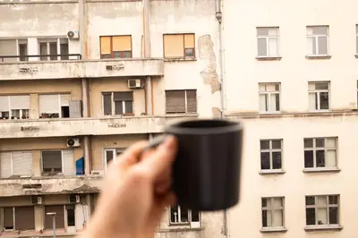a person holding a coffee cup in front of a building at Old Town Lounge Belgrade in Belgrade