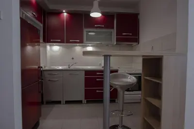 a kitchen with red cabinets and a sink and a stool at Slavija Square Apartments in Belgrade