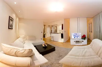 a living room with a white couch and a tv at Slavija Square Apartments in Belgrade