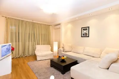 a living room with a white couch and two chairs at Slavija Square Apartments in Belgrade