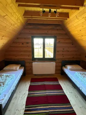 two beds in a room with a window and a rug at Lux Wood in Boljevci