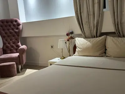 a bedroom with a bed and a pink chair at Panajota Apartment in city centre in Belgrade