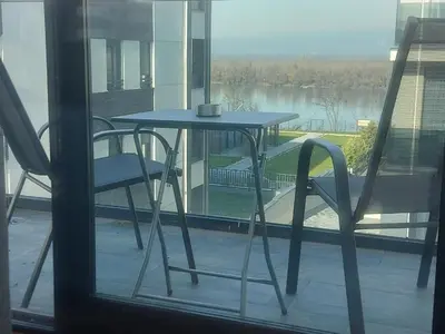 a table and chairs on a balcony with a view of a lake at Danube View 11 in Zemun
