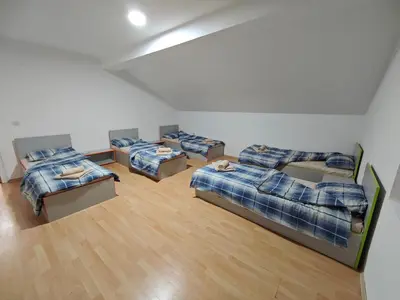 a room with four beds and a couch at Čiča 1 in Dobanovci