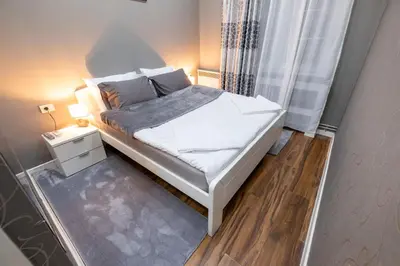 a small bedroom with a white bed and a window at Beo City Apartmani in Belgrade