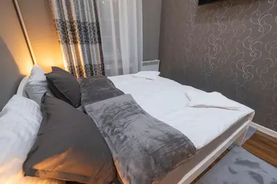 a bed with white sheets and pillows next to a window at Beo City Apartmani in Belgrade